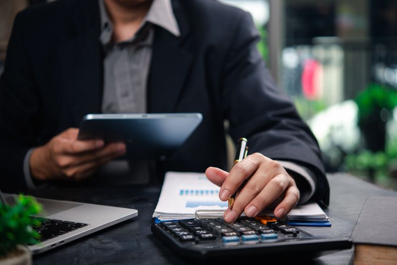Businessman accountant reviewing financial documents and using a tablet and calculator to plan business strategies and data analysis.