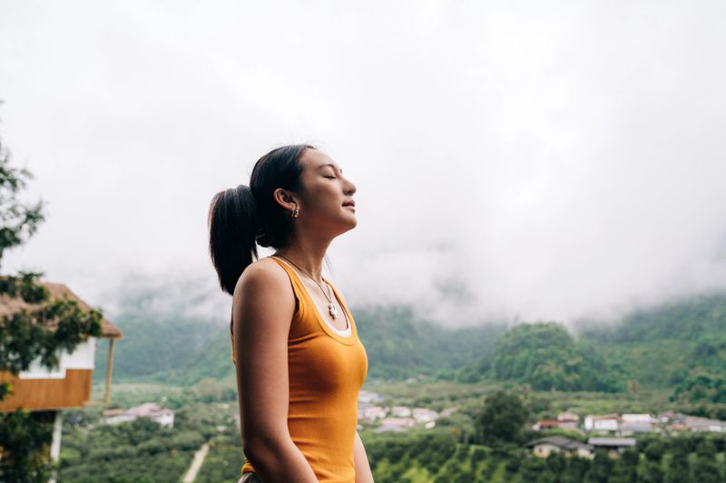 Woman Practicing Mindful Breathing Outdoors in Scenic Mountain Retreat