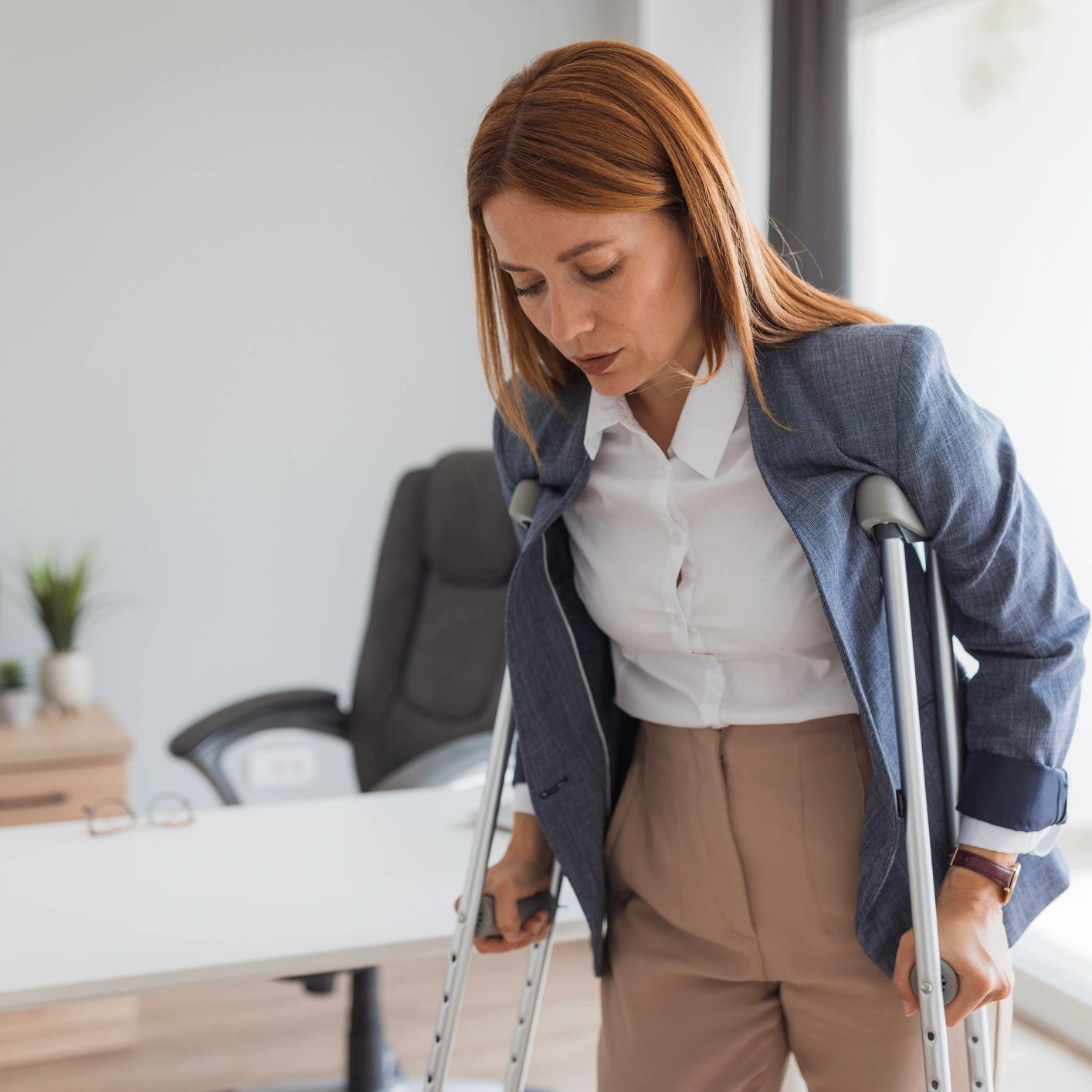 Woman using crutches inside an office.