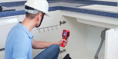 Technician inspects under-sink plumbing with a thermal camera.