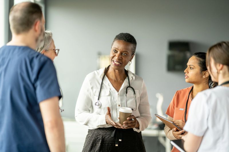 A group of healthcare professionals engaged in a conversation within a hospital environment, discussing patient care and collaboration. The composition conveys teamwork, professionalism, and the dedication of the medical field.