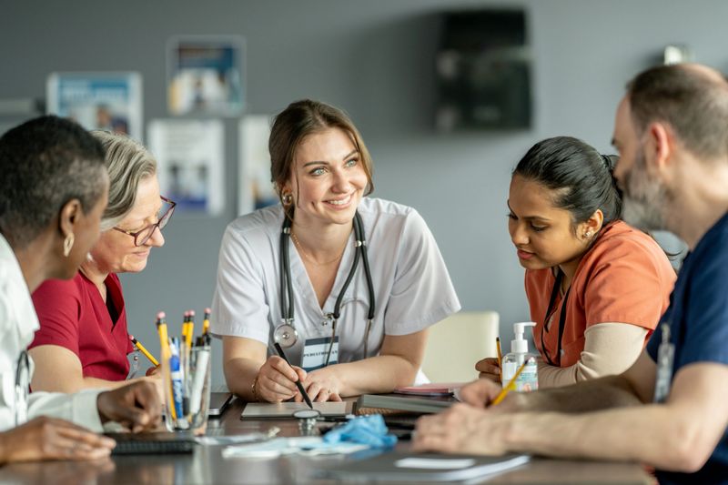 Diverse healthcare professionals gathered together, discussing patient care, showcasing teamwork and dedication in a modern medical environment.