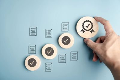 Hand arranging wooden tokens with check marks and quality icons.