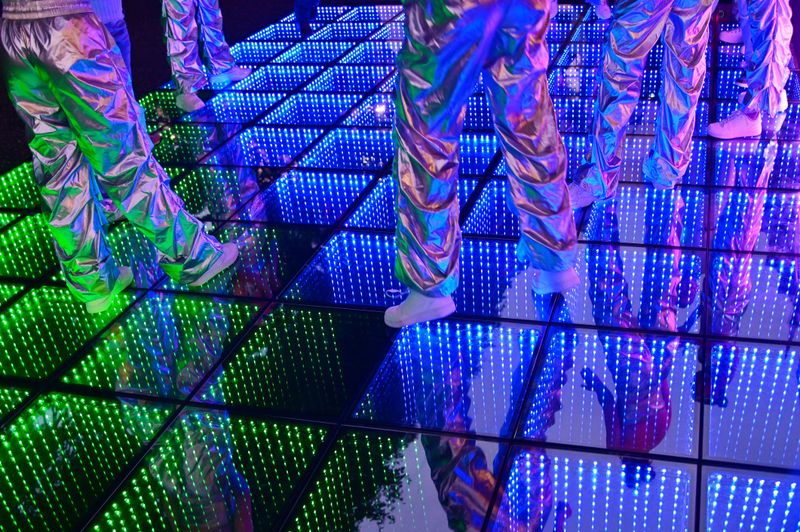 Unrecognizable group of people dancing on LED dance floor