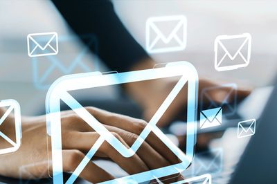 Hands typing on laptop surrounded by digital email icons.