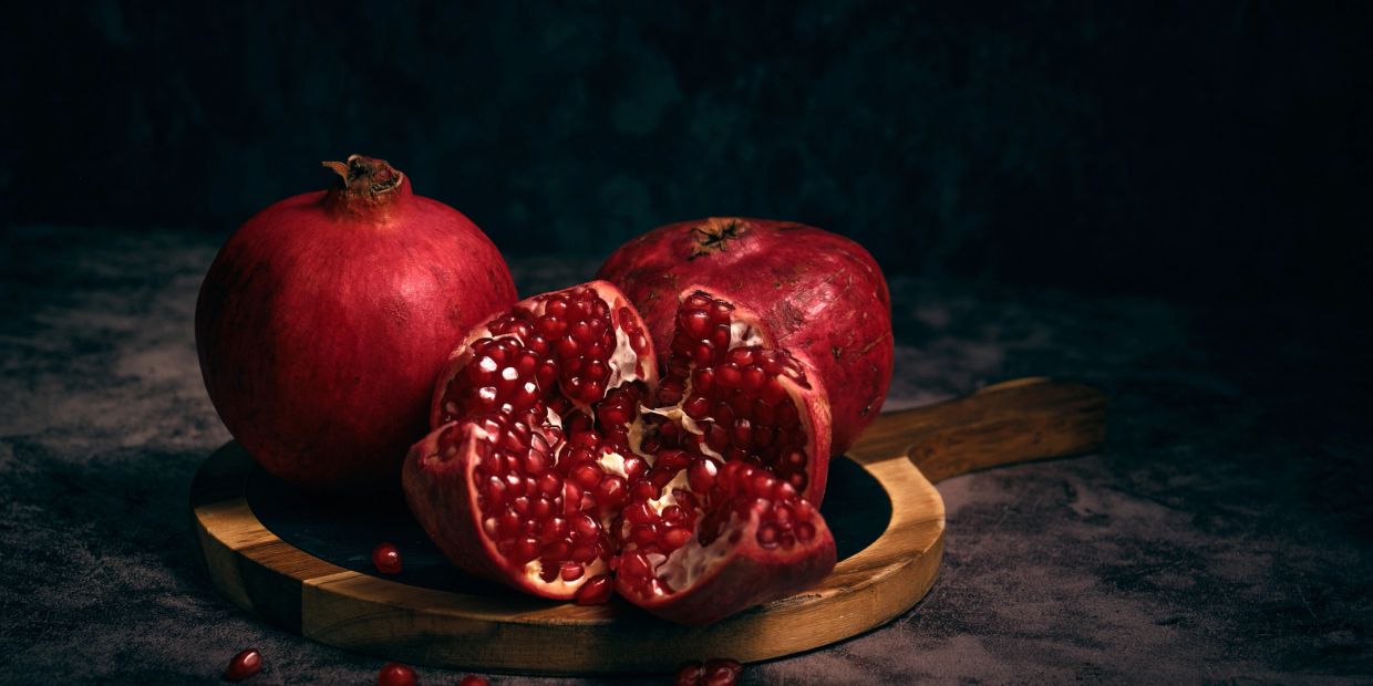 Fresh pomegranates on a wooden board.