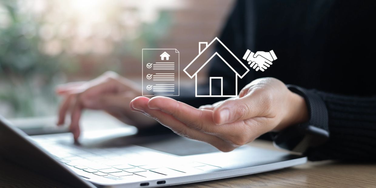 Person using a laptop with virtual real estate icons above their hand.