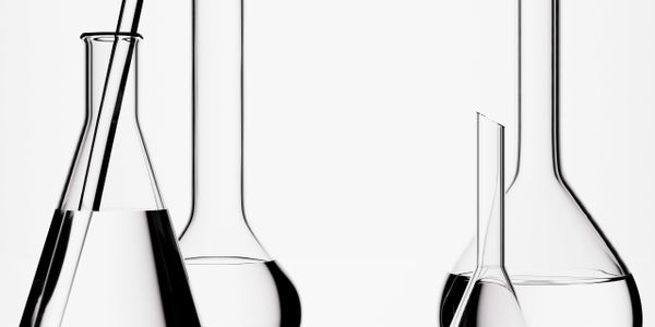 Clear laboratory glassware filled with liquid on a white background.
