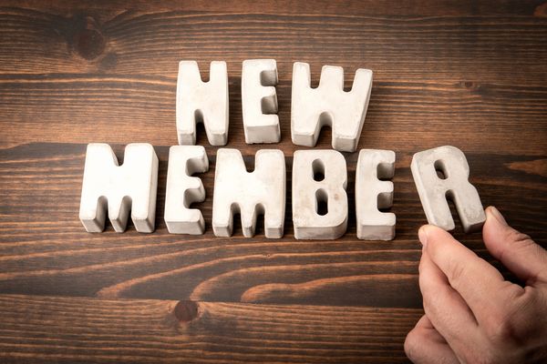 Letters spelling "NEW MEMBER" on a wooden surface.