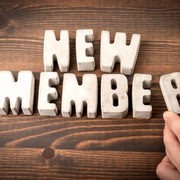 Wooden blocks spelling "NEW MEMBER" on a table.