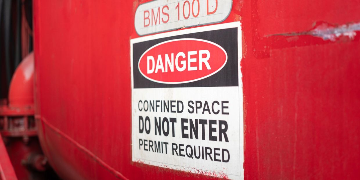 Construction worker entering a confined space using OSHA compliant safety equipment.