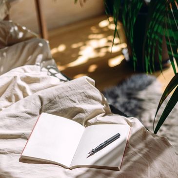 Notebook and pen on a cozy bed with sunlight.