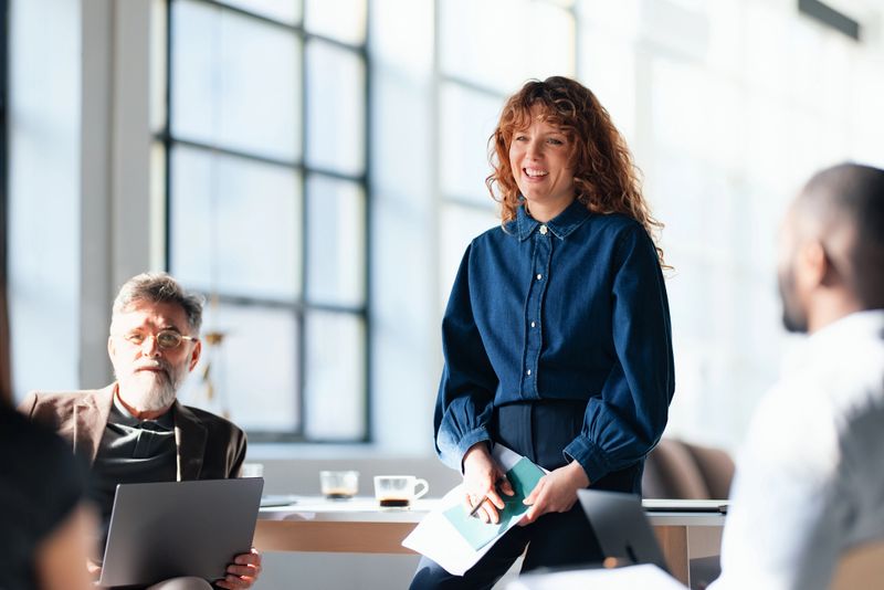 Professional colleagues engage in a productive meeting within a modern office, fostering teamwork and collaboration. The natural light highlights the dynamic interactions, emphasizing the cooperative and constructive business environment.
