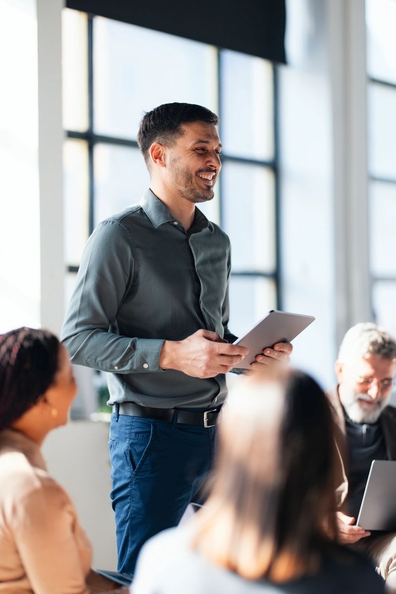 Confident business professional leading a team meeting in a bright modern office. Colleagues are actively engaged, fostering teamwork and collaboration within the professional workspace.