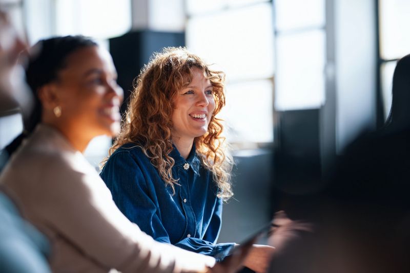 Two cheerful coworkers share ideas in a vibrant office setting, fostering a positive and collaborative workplace atmosphere.