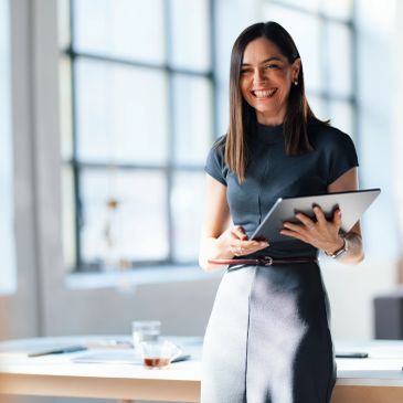 Smiling woman holding a tablet in a bright office.