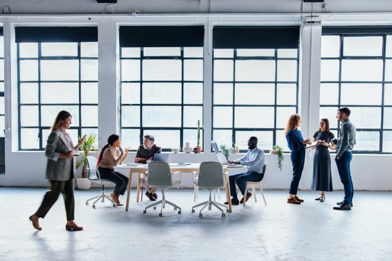 Diverse group of professionals working together in a contemporary coworking office. Collaborative conversation and productive focus create a vibrant yet professional workplace. Perfect blend of creativity and business in a modern environment.