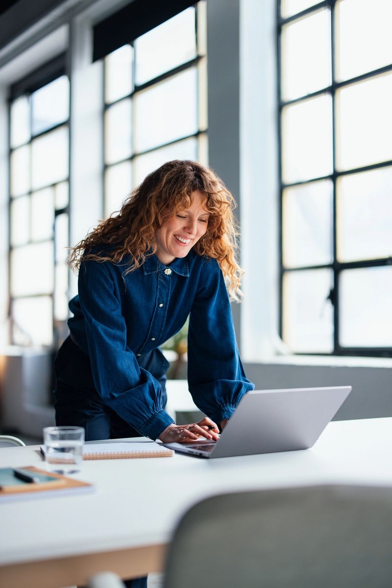Confident businesswoman at her desk using a laptop in a professionally lit workspace, conveying productivity and focus. Ideal for themes of business, technology, and modern work environments.