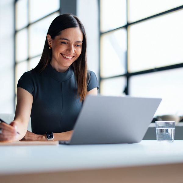 Smiling woman working on laptop in a bright, modern office.