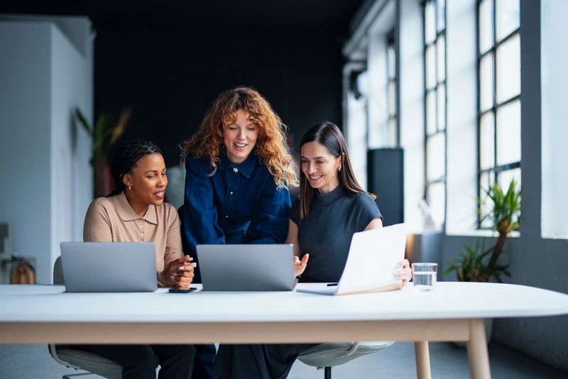 A team of women discussing at a workplace, showcasing collaboration, diversity, and professionalism in an office environment.