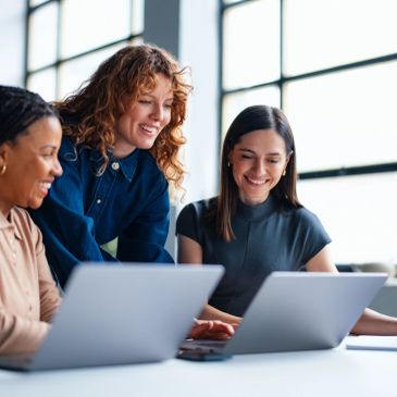 Drei Frauen arbeiten zusammen an Laptops.