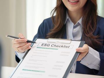 Woman holding and pointing to an ESG checklist on a clipboard.