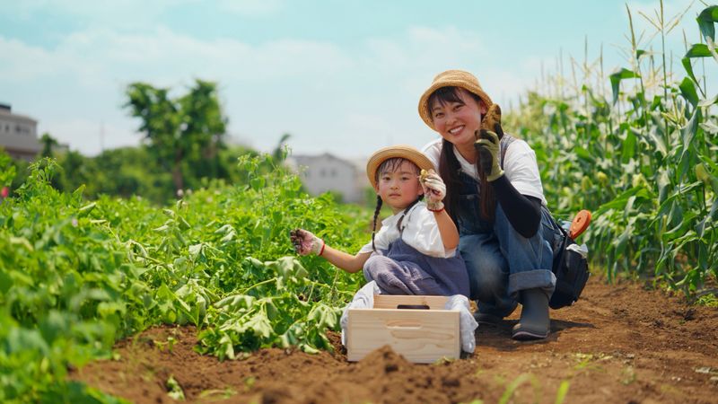 A happy mother and her small daughter are holding homegrown potatoes and looking at the camera and smiling in their farm.
