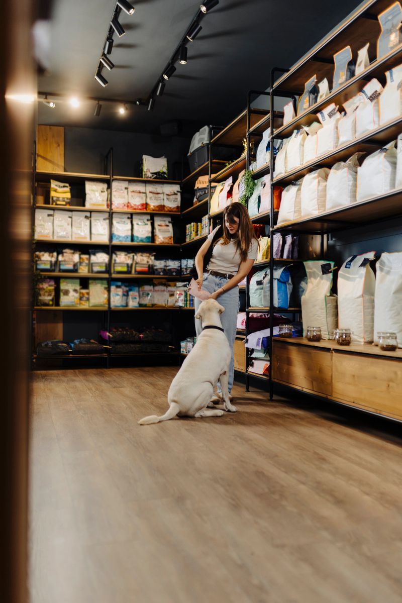 Young woman shopping with her dog in a modern pet store, choosing pet supplies and dog food together. Happy pet owner bonding with her dog a casual visit to the pet shop.
