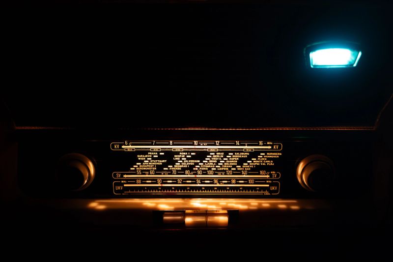A vintage retro radio with an illuminated dial glows warmly against a dark background, evoking a nostalgic and timeless atmosphere.