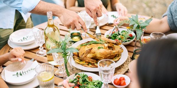 People enjoying a meal with roasted chicken and salads.