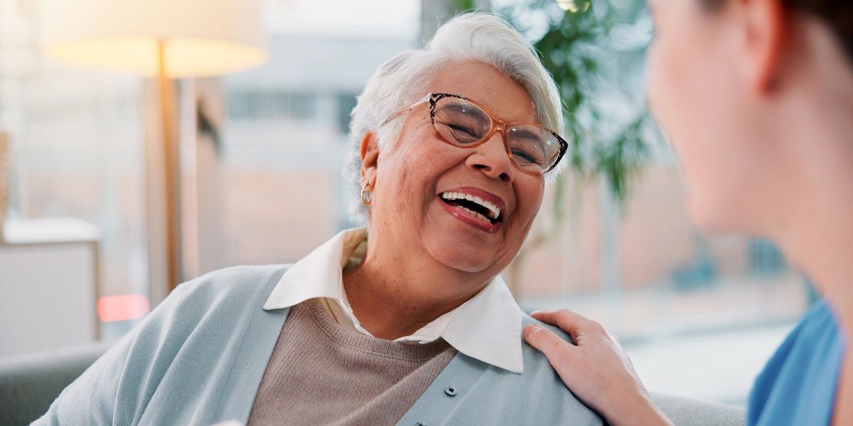 Elderly woman laughing with a caretaker.