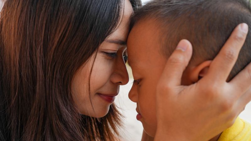 An intimate moment between mother and child, showcasing love and connection. mother gently holds her child head, creating warm and tender atmosphere filled with affection
