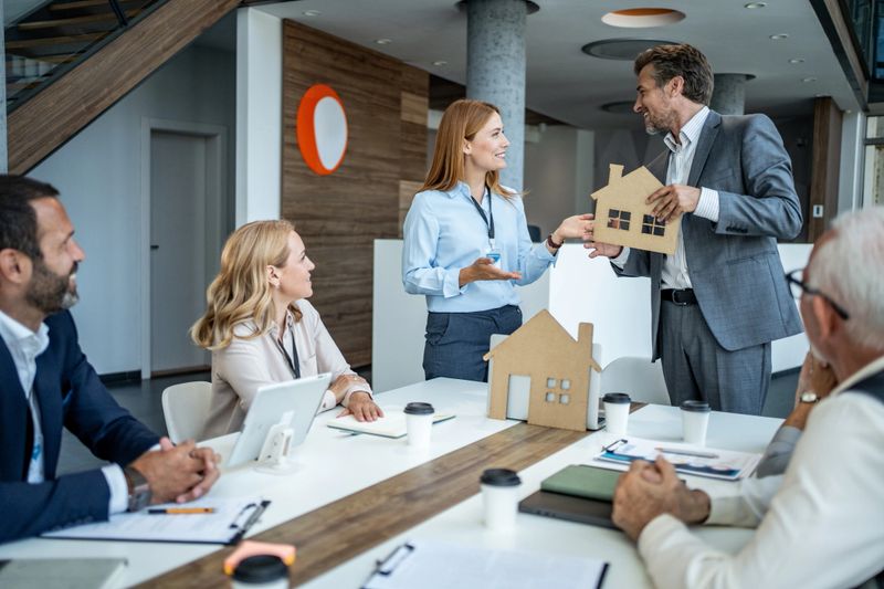 Group of real estate professionals having a meeting in a modern office, discussing housing market trends and investment opportunities using cardboard house models