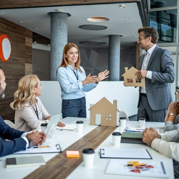 Real estate agents discussing property models in a meeting room.