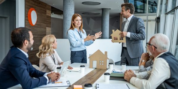 Business team discussing house models in a modern office meeting.