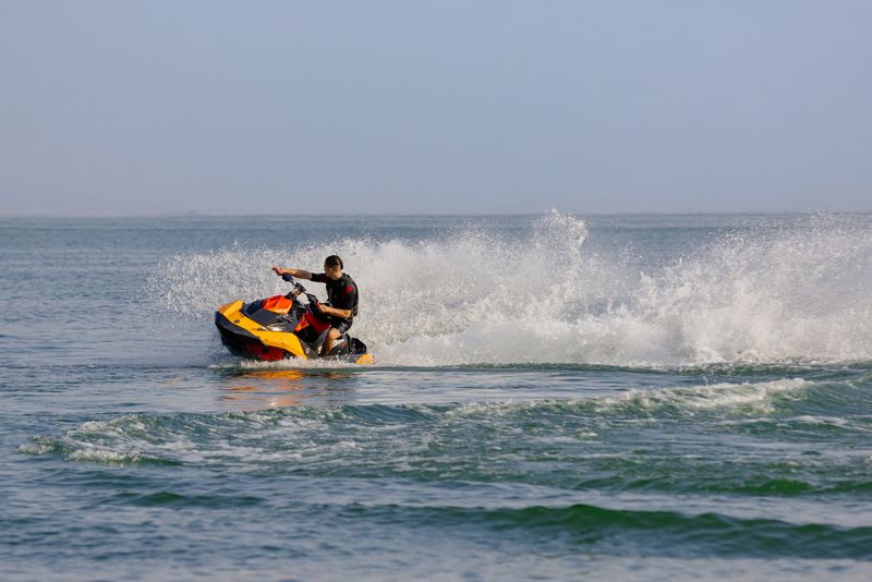 Man riding a jet ski across the water, creating splashes as he speeds over the surface.