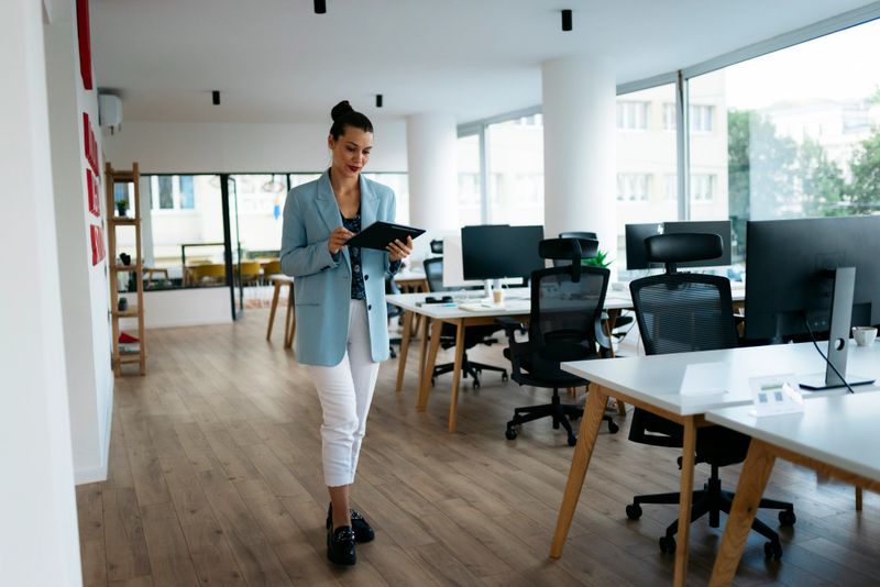 Businesswoman walking through modern office using digital tablet