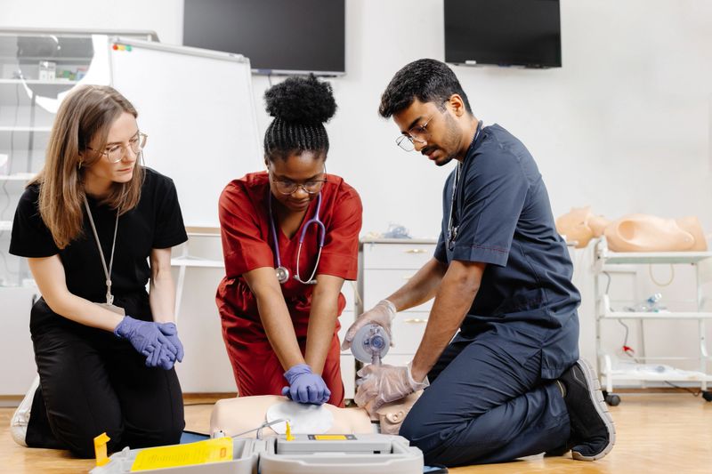 Diverse group of medical students practicing cpr on a medical manikin during first aid training in a hospital or clinic setting