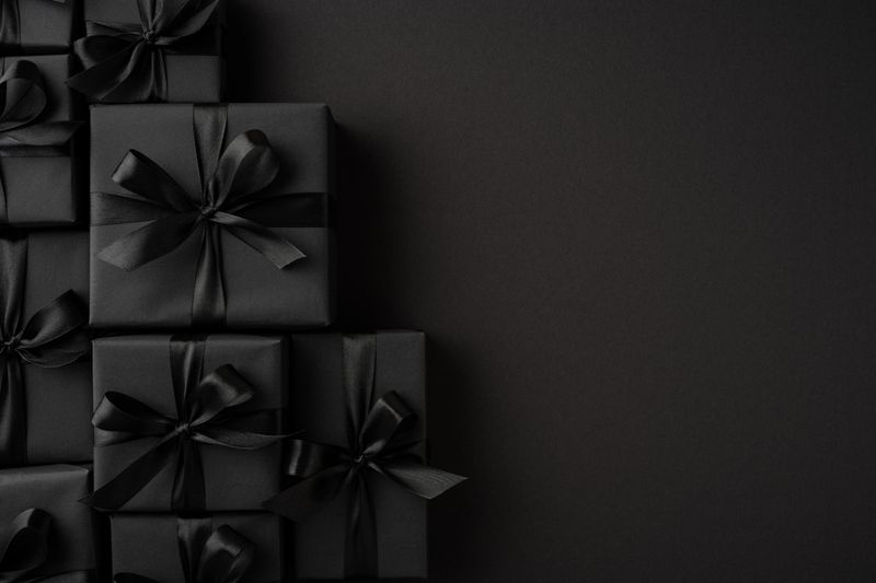 Luxurious black gift boxes with tied ribbons displayed on a solid dark backdrop enhancing the sophisticated look