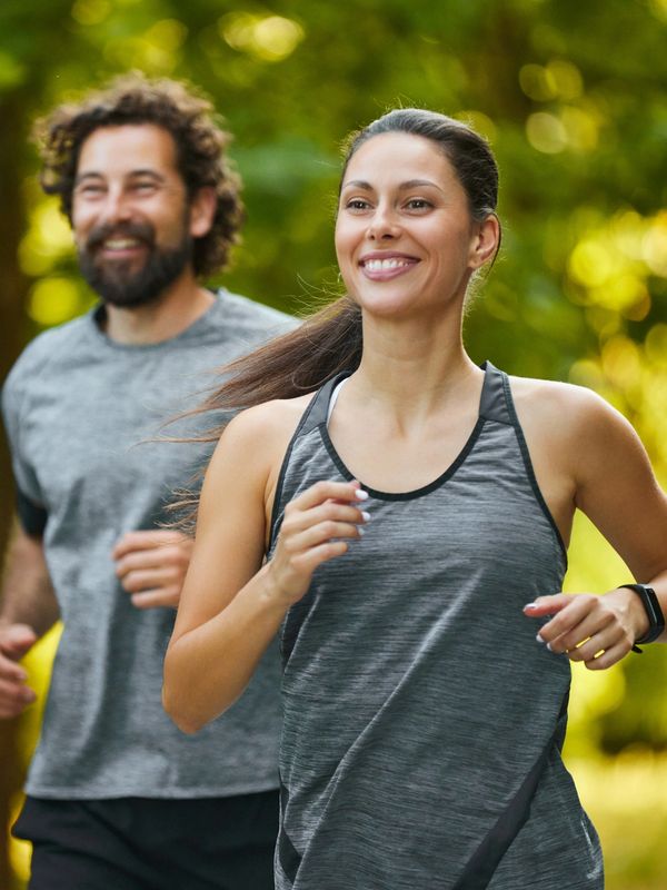 Two people jogging outdoors, smiling and enjoying.