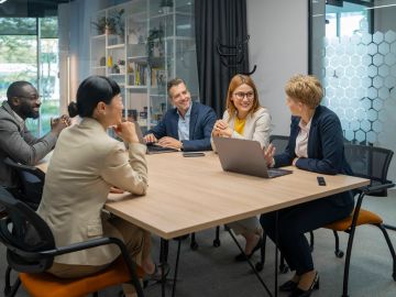 Two professionals analyze data on a large digital interface in a high-tech environment.