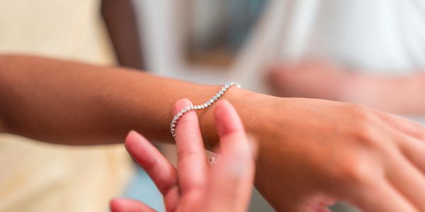 Someone putting a bracelet on a wrist.
