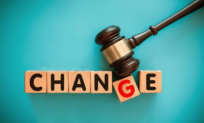Wooden blocks spell 'CHANGE' with a gavel on a blue background.