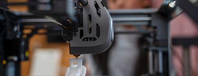 Close-up of a 3D printer creating a white object with a blurred background.