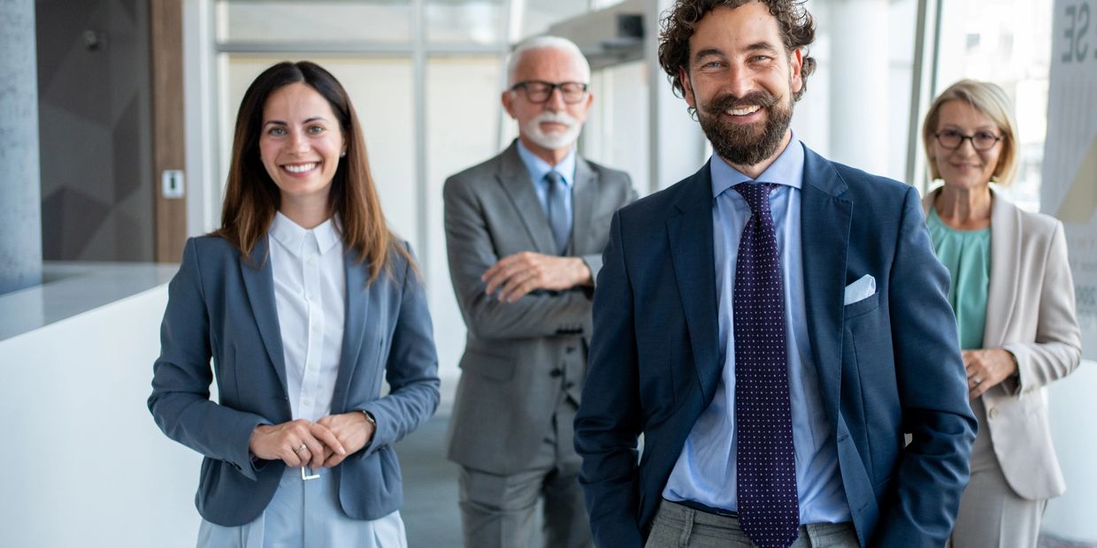 A group of four diverse professionals smiling at the camera.