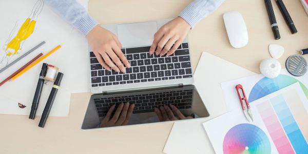Person working on a laptop at a creative workspace.