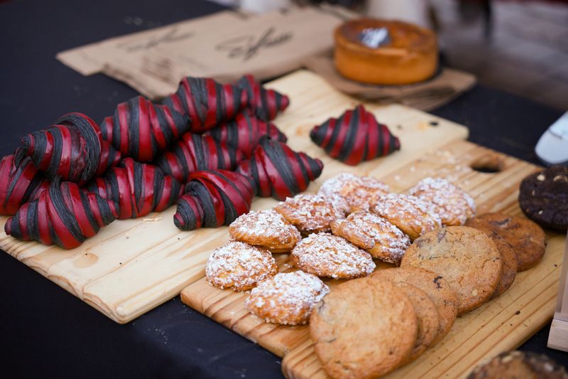 Close up of colorful croissants and baked cookies arranged on wooden boards at food market stand