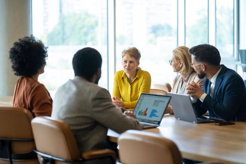 Business team analyzing financial data displayed on laptop screen during a meeting in a modern office