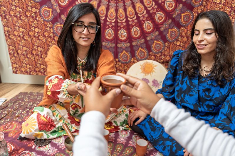 Three young women drinking organic cocoa during a traditional ceremony, promoting alternative medicine and healthy living