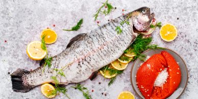Whole raw fish with lemon slices and herbs.